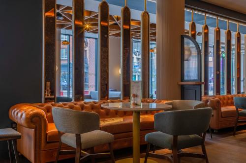 a restaurant with a leather couch and chairs at Hyatt Centric The Liberties Dublin in Dublin