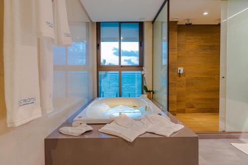 a bathroom with a bath tub with towels on the floor at Oceana Atlântico Hotel & SPA in João Pessoa