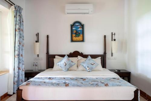 a bedroom with a large bed with blue pillows at Montego Bay Beach Village - Morjim in Morjim