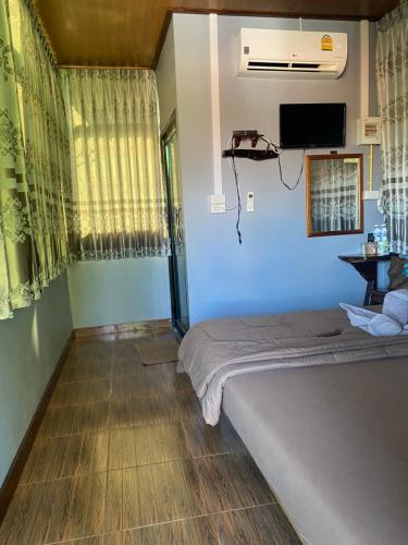 a bedroom with a bed and a tv on the wall at Maan Mork Khao Kho in Khao Kho
