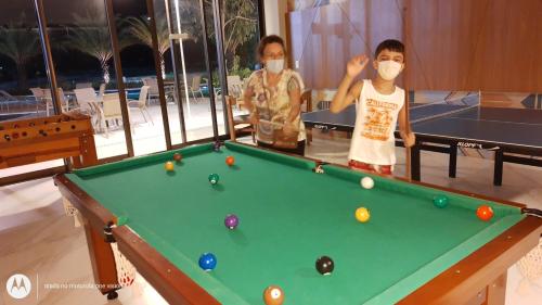 two boys wearing masks standing next to a pool table at Apartamento 2 quartos May Way Meireles uma quadra da Beira-mar in Fortaleza