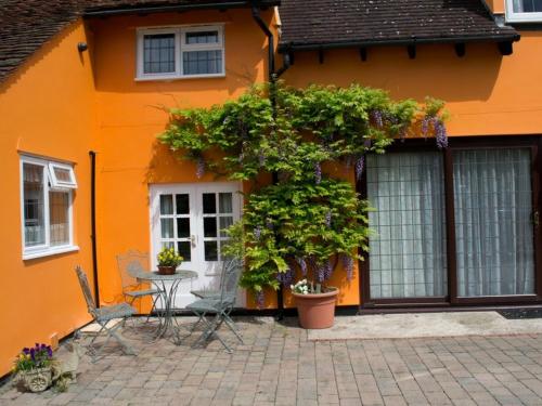 an orange house with a table and chairs in front of it at Woodview B&B Colchester in Birch
