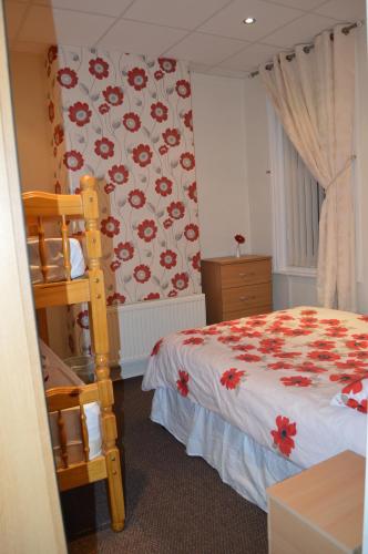 a bedroom with a bed with a red flower wallpaper at Ayrton House Holiday Apartments in Blackpool