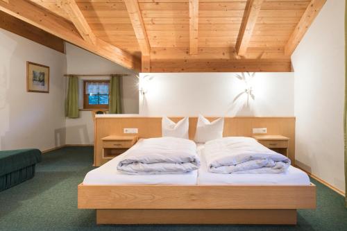 a bedroom with a large bed with a wooden ceiling at Ferienhof Schöne Aussicht in Pfunds