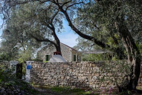 a house with a stone wall and a tree at Country house in Longós