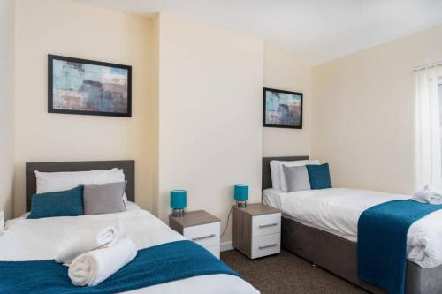 Duas camas num quarto com azul e branco em Cosy Stay Swansea - TV in every bedroom em Swansea