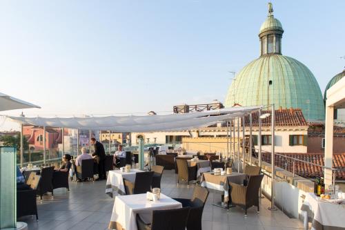 a restaurant with tables and chairs on a roof at Hotel Carlton On The Grand Canal in Venice