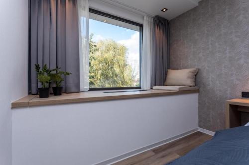 a bedroom with a window with two potted plants on a window sill at Hotel de Rousch - 4 sterren Superieur in Heerlen