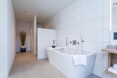 a white bathroom with a tub and a sink at Hotel de Rousch - 4 sterren Superieur in Heerlen