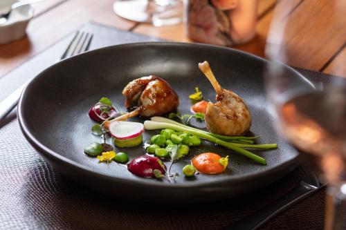 a black plate with meat and vegetables on a table at Vik Chile in San Vicente de Taguatagua