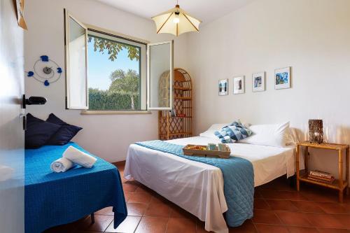 a bedroom with two beds and a window at Casa Vacanza Ondablu CaseSicule, on the Beach with big Veranda and Wifi in Santa Maria Del Focallo