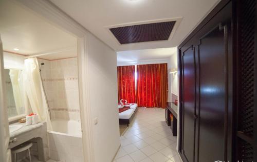 a bathroom with a sink and a red curtain at Hotel Liberty Resort in Monastir