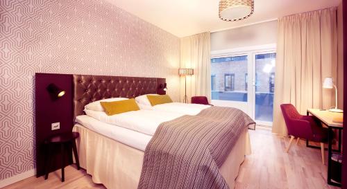 a hotel room with a large bed and a desk at Home Hotel Astoria in Hamar