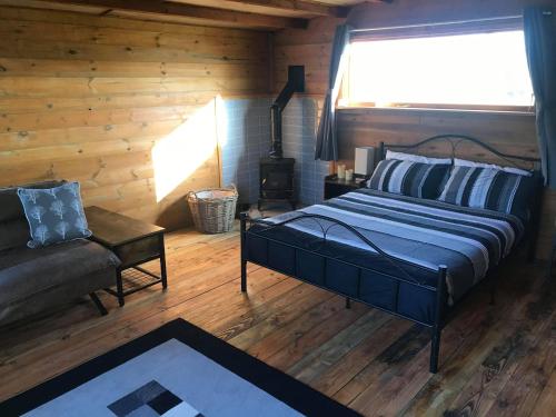 a bedroom with a bed and a couch and a window at Old Mill House Log Cabins in Dorchester