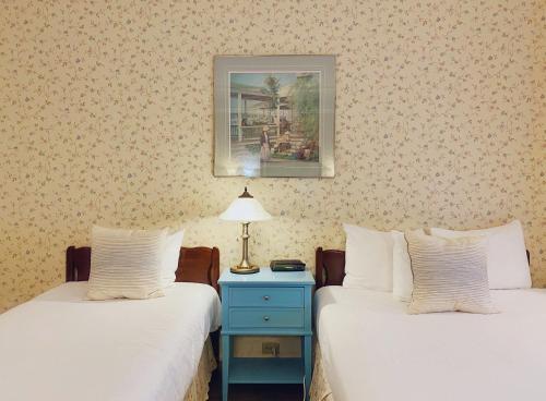 a room with two beds and a nightstand with a lamp at Le Chateau de Pierre in Quebec City