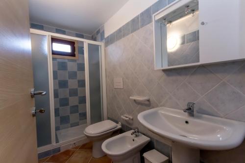 y baño con lavabo, aseo y espejo. en Residence Aquafantasy, en Isola Rossa