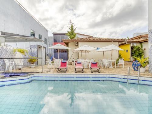 een zwembad met stoelen en parasols naast een huis bij OYO Hotel Stella Maris - Salvador in Salvador