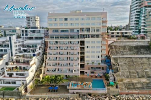 曼塔的住宿－曼塔霍斯特酒店，一座高大的建筑,前面有一个游泳池