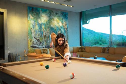 a woman playing pool in a room with a pool table at Vik Chile in San Vicente de Taguatagua