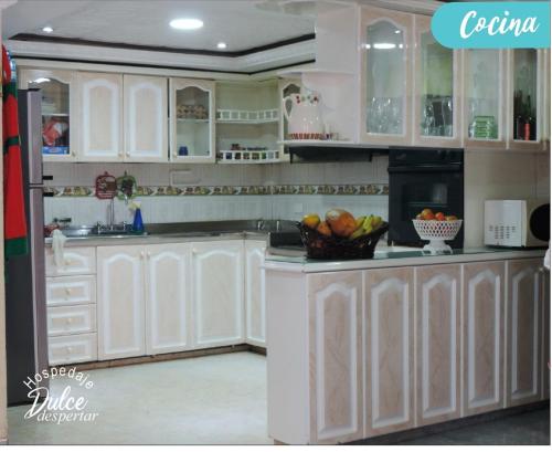- une cuisine avec des placards blancs et un bol de fruits sur le comptoir dans l'établissement Hospedaje Dulce Despertar, à Sogamoso
