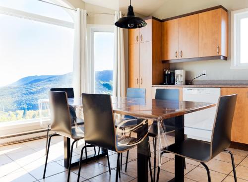 een keuken met een eettafel en stoelen bij Panoramique - 2 logements, spa, massif et vue splendide in Petite-Rivière-Saint-François