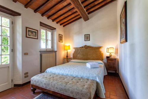 a bedroom with a bed and two windows and two lamps at Villa Serena & Dépendances in Cortona