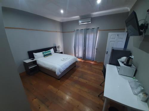 - une petite chambre avec un lit et du parquet dans l'établissement Lux Rooms on 37, à Bloemfontein