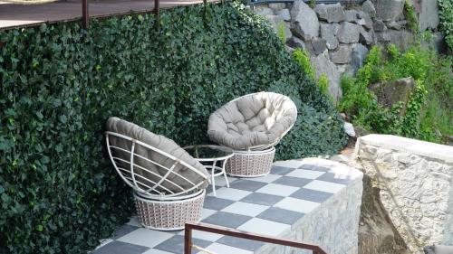 two chairs sitting on a patio next to a hedge at Спа-Готель Потоки Хауз in Kam”yani Potoky