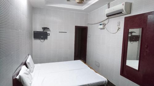 a small room with a bed and a mirror at lawrence lodge in Nāgercoil