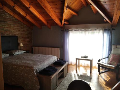 um quarto com uma cama, uma janela e uma cadeira em La Rocosa em Muriedas