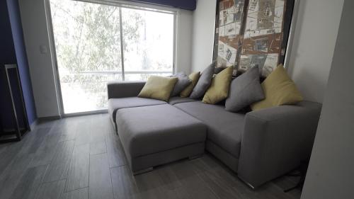 a living room with a gray couch with yellow pillows at One Bedroom Apartment Del Valle in Mexico City