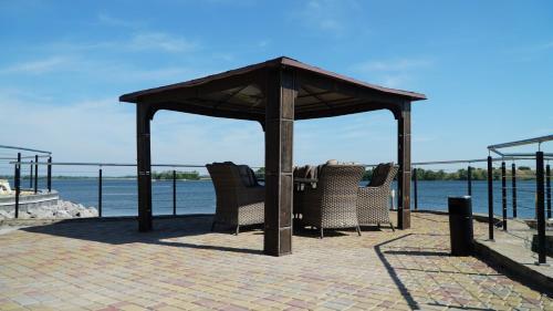a gazebo with chairs sitting under it next to the water at Спа-Готель Потоки Хауз in Kam”yani Potoky