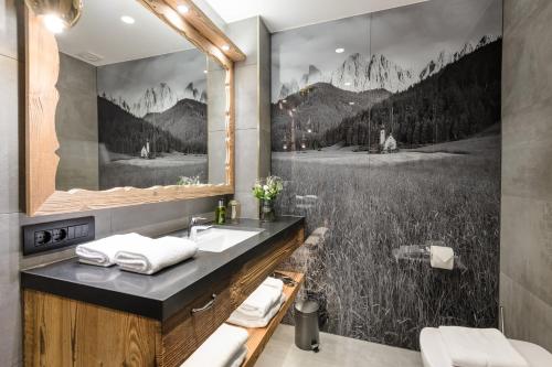 een badkamer met een wastafel en een foto van de bergen bij MONDI Hotel Tscherms in Cermes