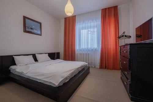 a bedroom with a bed and a dresser and a window at Апартаменты Петровские 90 кв в центре с хорошим видом in Tomsk