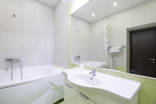 a white bathroom with a sink and a bath tub at Апартаменты Петровские 90 кв в центре с хорошим видом in Tomsk