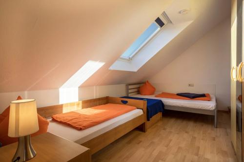 two beds in a attic room with a window at Ferienhof Sauter Friedrichshafen in Neukirch