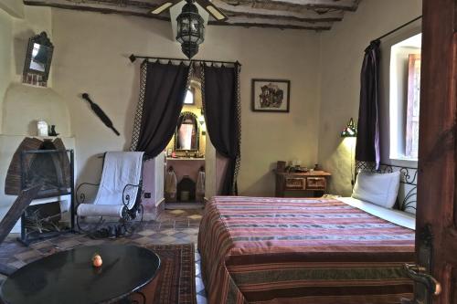 Un dormitorio con una cama, una mesa y una silla. en Sawadi Ecolodge, en Skoura