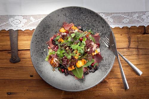 a plate of salad on a table with a fork at Hotel Central - das kleine Boutique Hotel am Achensee in Pertisau