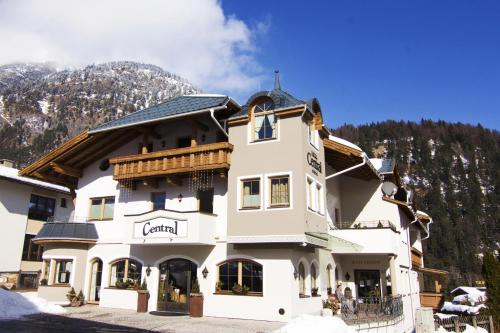 a large white building in front of a mountain at Hotel Central - das kleine Boutique Hotel am Achensee in Pertisau