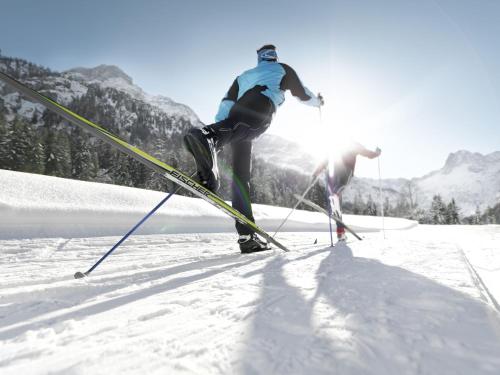 two people on skis jumping in the snow at Hotel Central - das kleine Boutique Hotel am Achensee in Pertisau