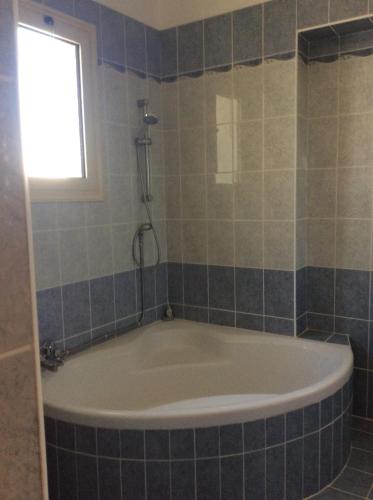 La salle de bains est pourvue d'une baignoire et d'une fenêtre. dans l'établissement Quality Villa with Pool in Superb Location in Paphos, à Mandria
