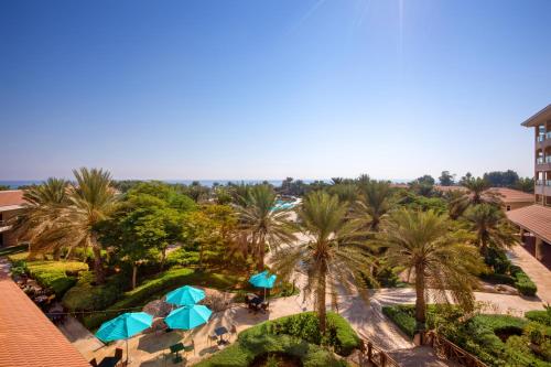 een uitzicht over een resort met palmbomen en parasols bij Fujairah Rotana Resort & Spa - Al Aqah Beach in Al Aqah