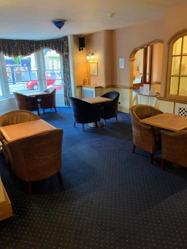 uma sala de jantar com mesas, cadeiras e janelas em Yelf's Hotel em Ryde