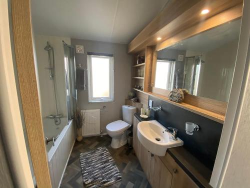 a bathroom with a sink and a toilet at Brand new Sea view beach lodge Trecco bay 3 bedroom in Porthcawl