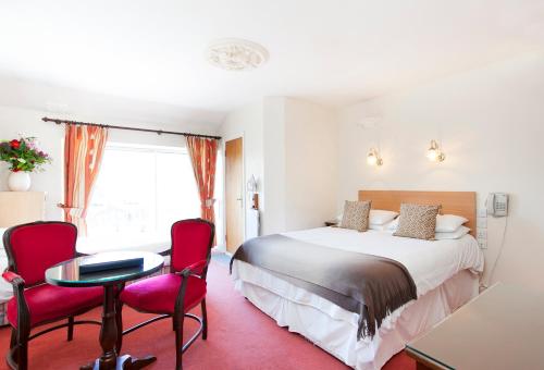 Habitación de hotel con 1 cama y 2 sillas rojas en Leeson Bridge Guesthouse, en Dublín