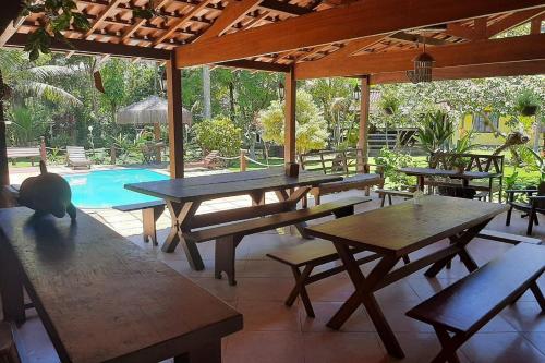 eine Terrasse mit Tischen und Stühlen sowie einem Pool in der Unterkunft Pousada Recanto dos Lima in Praia do Bananal