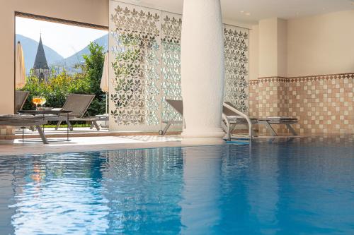 een zwembad met stoelen en een tafel en een gebouw bij MONDI Hotel Tscherms in Cermes