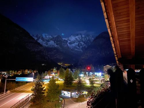 a person taking a picture of a city at night at Hotel Walser Courmayeur in Courmayeur