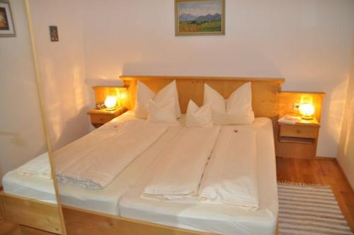 a bedroom with a large white bed with two lights at Taffenreutherhof in Achenmühle