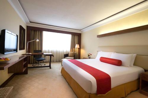 a hotel room with a bed and a desk and a television at Marco Polo Plaza Cebu in Cebu City